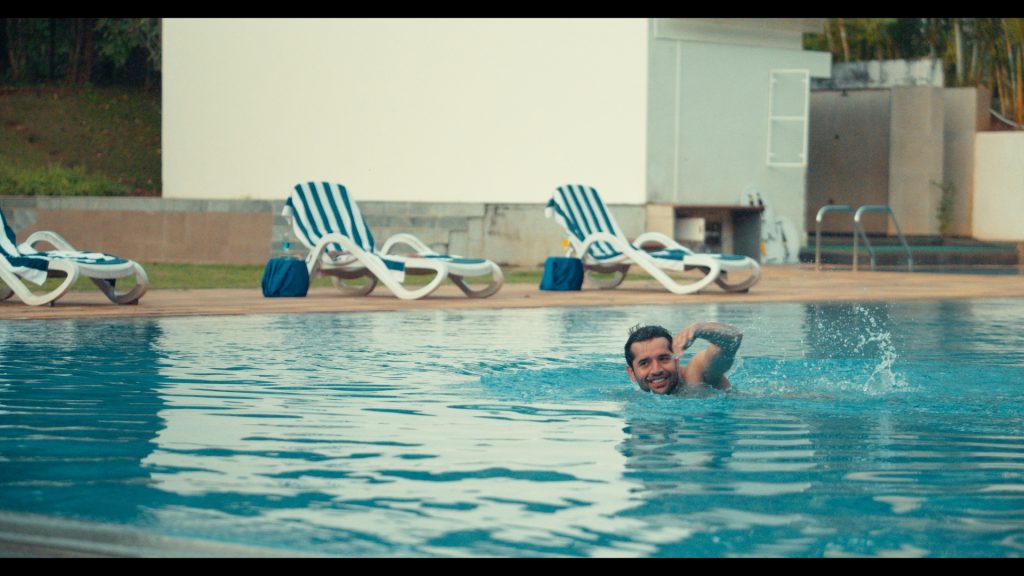 Man swimming in a luxurious outdoor pool at the best resorts in Dandeli | Whistling Woodzs